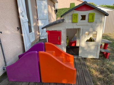 a little house with a slide and a play house in the back yard