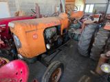 an old tractor in a garage with other old tractors