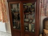 une armoire en bois avec une porte vitrée, devant laquelle se trouve une chaise