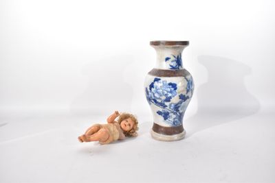 un vase bleu et blanc posé à côté d'une petite figurine