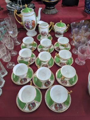 many cups and saucers on a table with a red table cloth