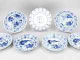 six blue and white plates and a bowl on a white surface