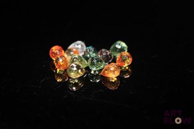Plusieurs pierres précieuses de différentes couleurs sont disposées sur une surface noire.