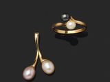 une paire de boucles d'oreilles en perles et une bague en or sur fond noir