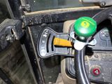 a steering wheel of a tractor with a green knob