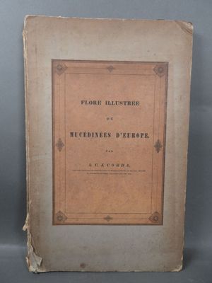 an old book sitting on top of a table next to a gray wall