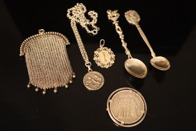 several silver items are displayed on a black surface with a coin
