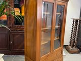 a tall wooden cabinet with a glass door in a room