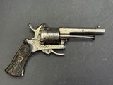 un revolver argenté avec une crosse noire sur un fond gris