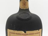 an old bottle of liquor sitting on top of a white surface