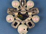 a silver brooch with pearls on it on a blue surface