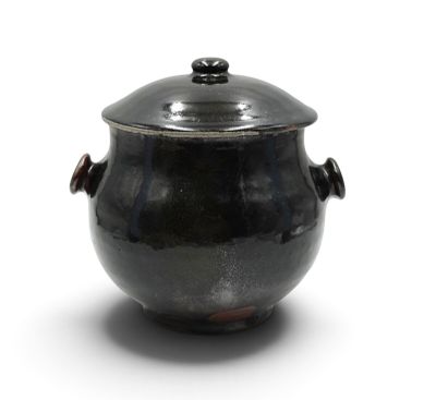 une casserole noire avec un couvercle posée sur une surface blanche