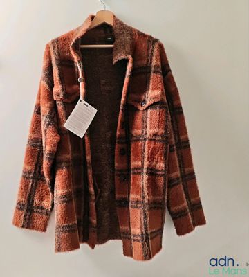 une veste à carreaux orange et marron suspendue à un cintre