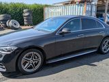 La Mercedes Classe S berline est garée devant un tas de pneus