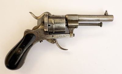 un vieux revolver avec une poignée en bois sur une surface blanche