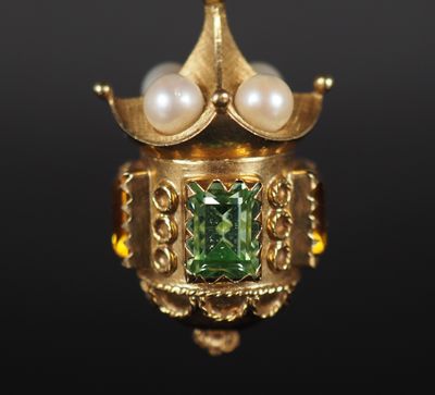un gros plan sur une bague en or ornée de perles et d'une pierre verte