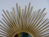 a gold sunburst mirror on a white wall