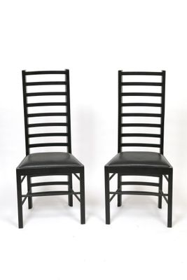 pair of black dining chairs with black leather upholstered seats