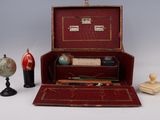 une valise rouge contenant un stylo, un globe terrestre et d'autres objets