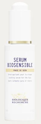 un gros plan d'un flacon de sérum posé sur une surface blanche