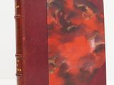 un vieux livre à la couverture rouge posé sur une table blanche