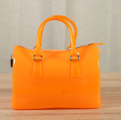 an orange handbag sitting on top of a table next to a curtain