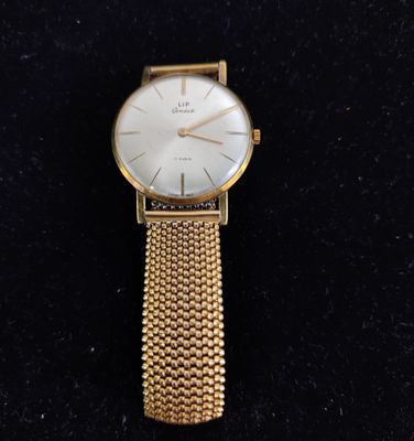 a close up of a gold watch on a black surface