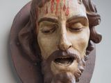 a statue of jesus with blood on his face on the wall