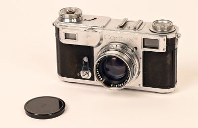 un petit appareil photo et une petite pièce de monnaie posés sur une surface blanche