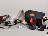 a camera, a camera case, a lens, and other items on a table