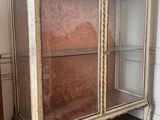 an antique display cabinet with glass doors in a room