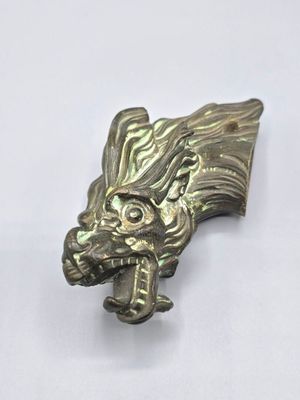 une image représentant une tête de dragon en métal sur un fond blanc