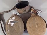 two flasks and a cup on a white table