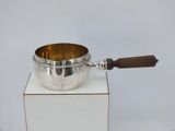 a silver bowl with a wooden handle on a white pedestal