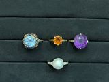 trois pierres précieuses de couleurs différentes et une bague avec une perle, posées sur un fond noir