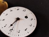 a close up of a clock on a table with a coin