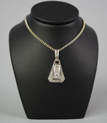 an art deco diamond pendant on a gold chain on a mannequin