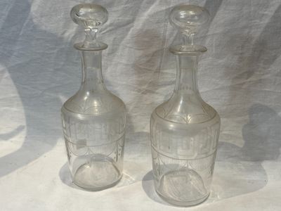 two empty glass bottles sitting next to each other on a table