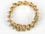Gros plan sur un bracelet en or orné de pierres bleues