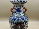 un vase avec un oiseau posé sur une table
