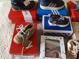 many pairs of shoes on a bed with a picture of a baby