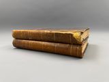 two old books sitting on top of each other on a table