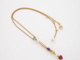 a gold necklace with multi colored stones and pearls on a white background