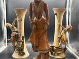 une statue représentant une femme en robe et trois vases
