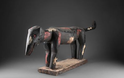 une photo d'une sculpture en bois représentant un chien, posée sur un socle en bois