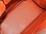 the inside of an orange purse with a brown leather handle