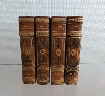 Quatre vieux livres sont alignés sur une table en verre