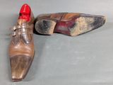 pair of brown shoes with red soles sitting on a gray surface