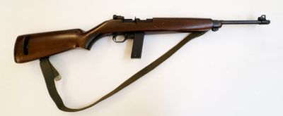 un fusil muni d'une sangle, posé sur une surface blanche