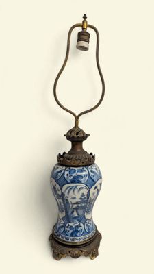 a blue and white vase with a bell on top of it